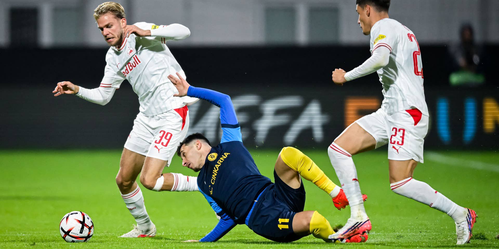 Zwei Spieler von Salzburg kämpfen mit einem Spieler von Celje während eines Fußballspiels um den Ball.