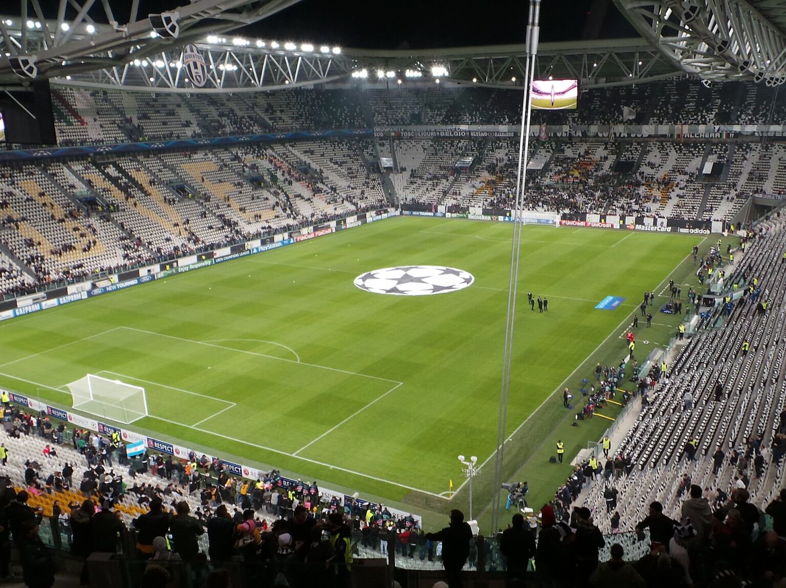 Floodlit interior of Allianz Stadium in Turin with pitch and partly filled stands