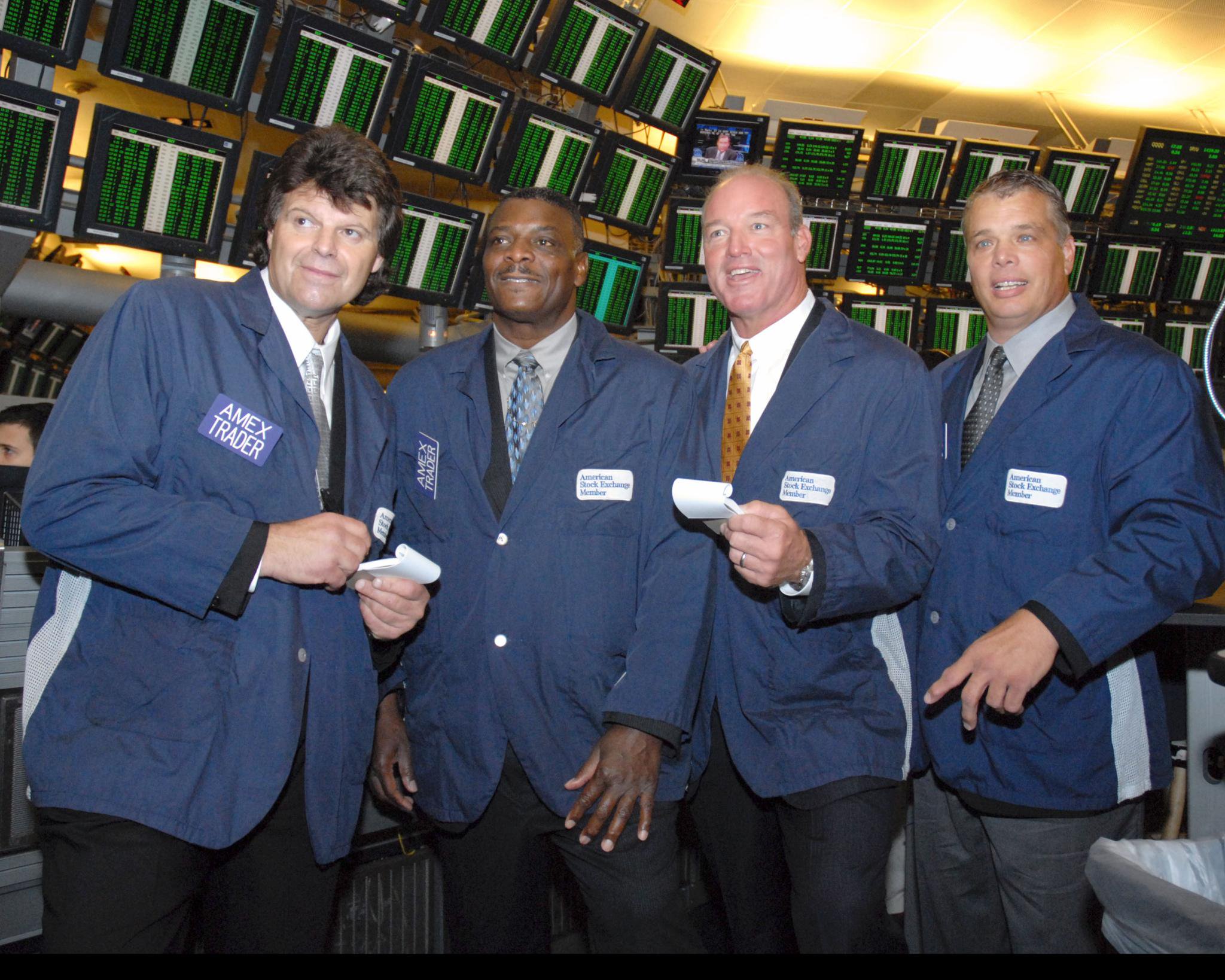 Mark Gastineau, Abdul Salaam, Marty Lyons and Joe Klecko of the New York Jets Sack Exchange stand on the trading floor of the American Stock Exchange wearing blue trader jackets.