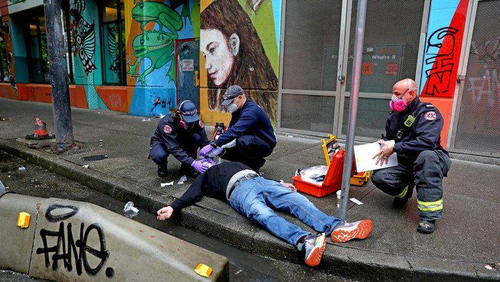 VANCOUVER, BRITISH COLUMBIA - MAY 05: Medics with the Vancouver Fire Rescue Services attend to a man who overdosed on drugs in the Downtown Eastside (DTES) neighborhood on Thursday, May 5, 2022 in Vancouver, British Columbia. A by stander witnessed the man collapse, then gave him two injections of Naloxone, a medicine that rapidly reverses an opioid overdose, and sent another person to get an oxygen tank from a supervised consumption site. Supervised consumption sites in the DTES give addicts who use fentanyl, opioids, crystal methamphetamine and other drugs a place to use and get harm reduction supplies; clean syringes, alcohol swabs, sterile water, tourniquets, spoons and filters. On April 14, 2016, provincial health officer Dr. Perry Kendall declared a public health emergency under the Public Health Act due to the significant rise in opioid-related overdose deaths reported in B.C. since the beginning of 2016. (Gary Coronado / Los Angeles Times via Getty Images)