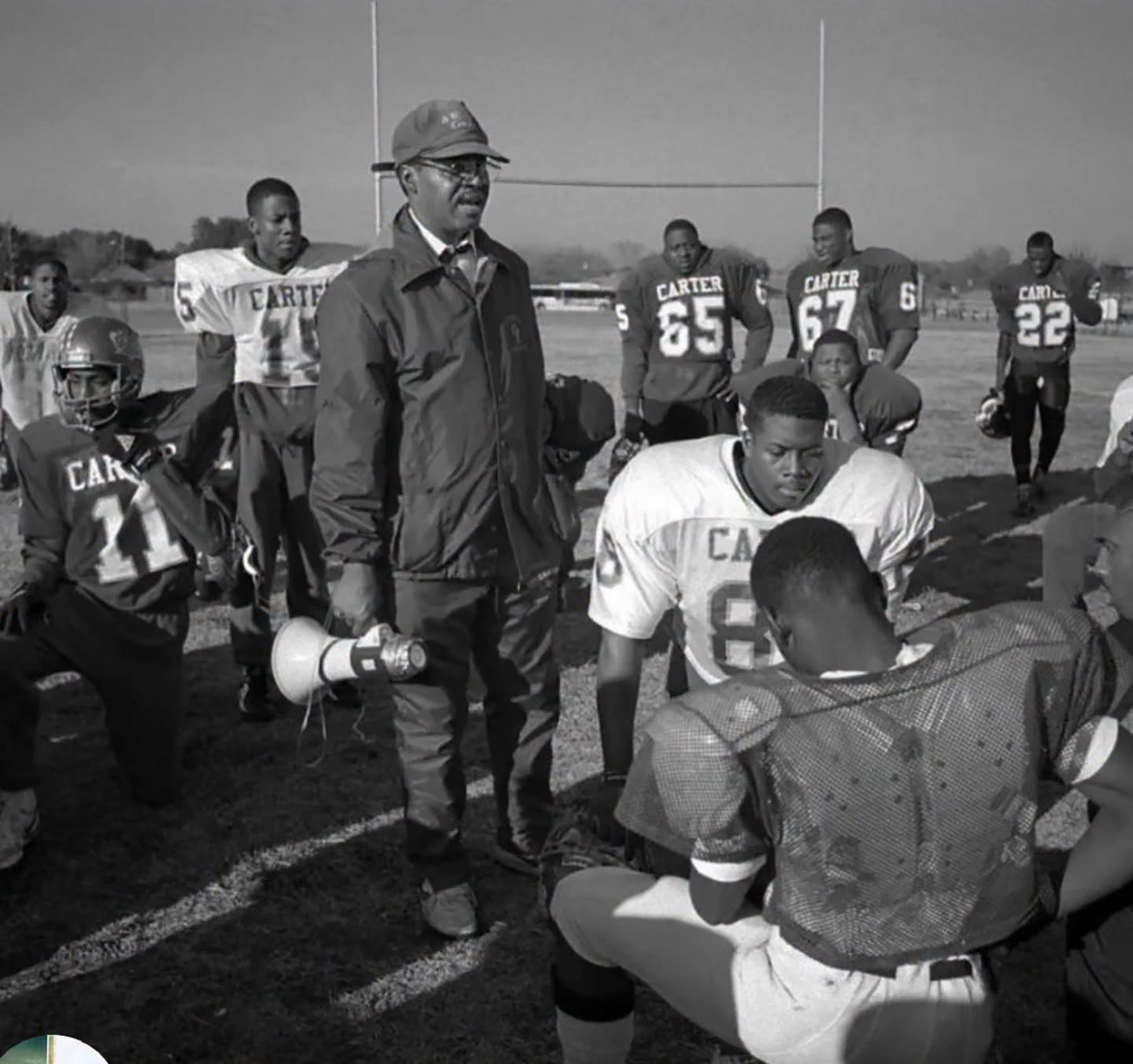 Coach Freddie James holding a megaphone while standing with the Carter High School football team.