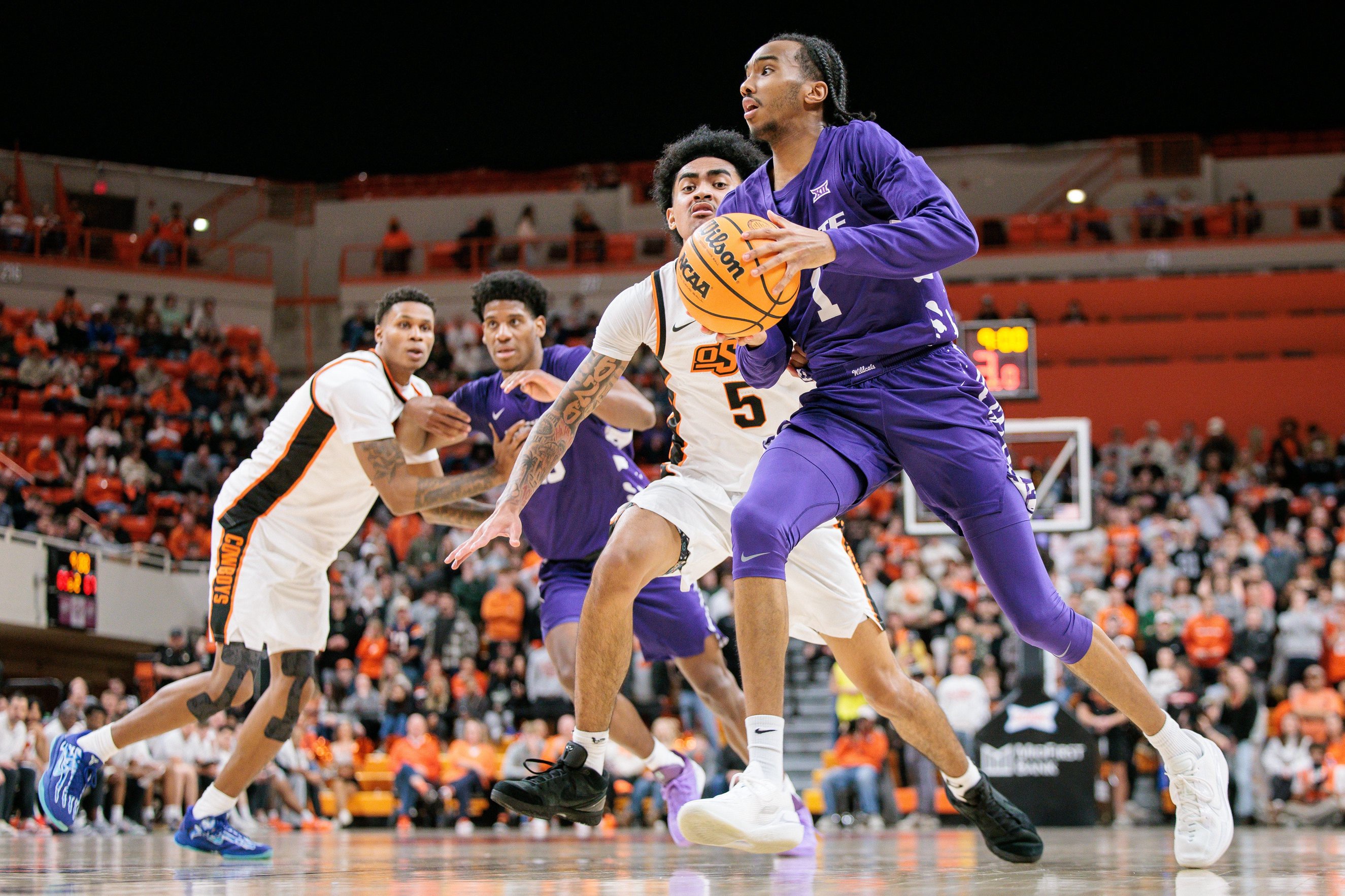 Jan 17, 2026; Stillwater, Oklahoma, USA; Abdi Bashir Jr. (1) of the Kansas State Wildcats drives to the basket around Vyctorius Miller (5) of the Oklahoma State Cowboys during the second half at Gallagher-Iba Arena. Mandatory Credit: William Purnell-Imagn Images