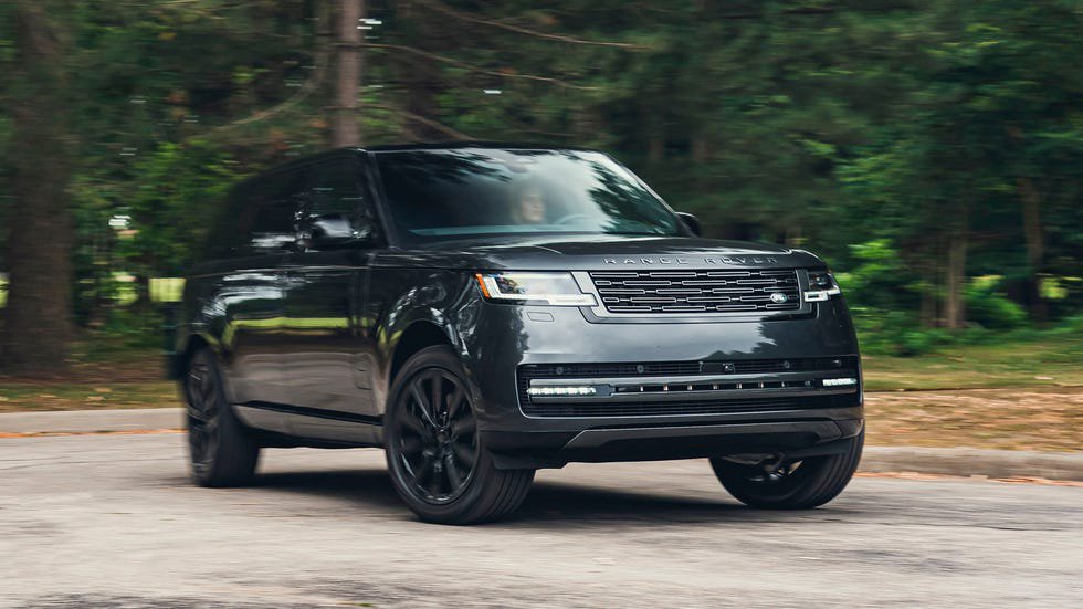Black luxury SUV in motion surrounded by green trees.
