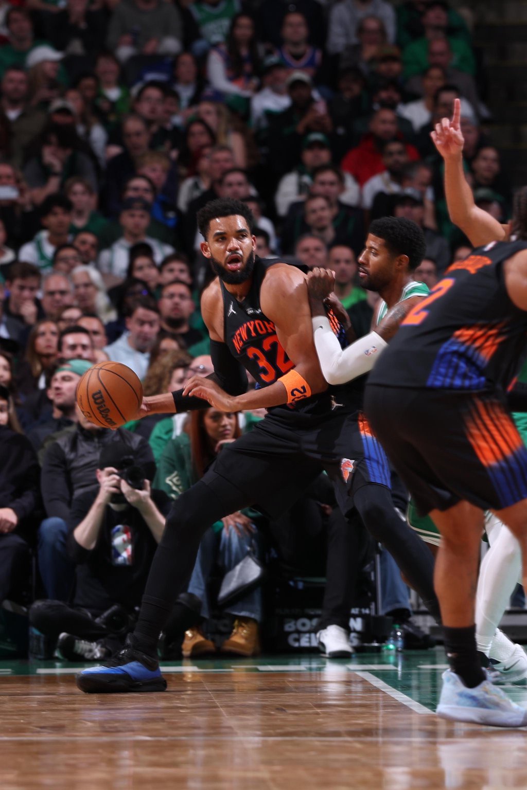Karl-Anthony Towns of the New York Knicks dribbles the ball past a Boston Celtics defender.