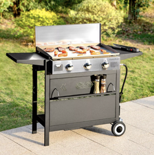 Outdoor grill with sausages and meat cooking on the griddle, positioned on a patio beside a grassy area. BBQ season made easy for shoppers