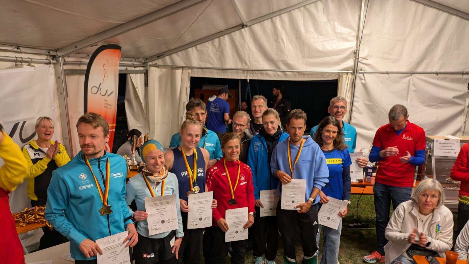 Siegerehrung der Deutschen Meisterschaft im 6-Stundenlauf in Schwindegg mit den erfolgreichen Läuferinnen und Läufern, die ihre Urkunden und Medaillen im Festzelt präsentieren.