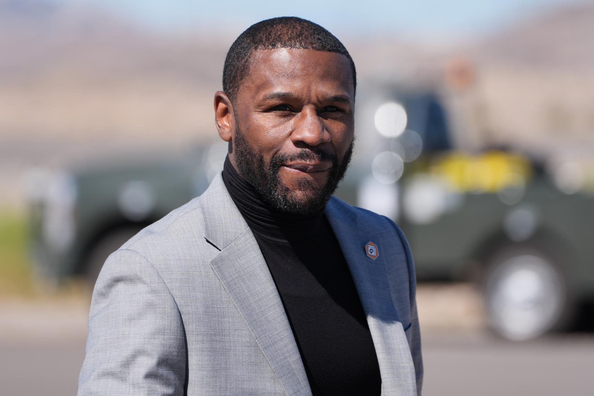 Floyd Mayweather Jr. wearing a gray suit and a black turtleneck.