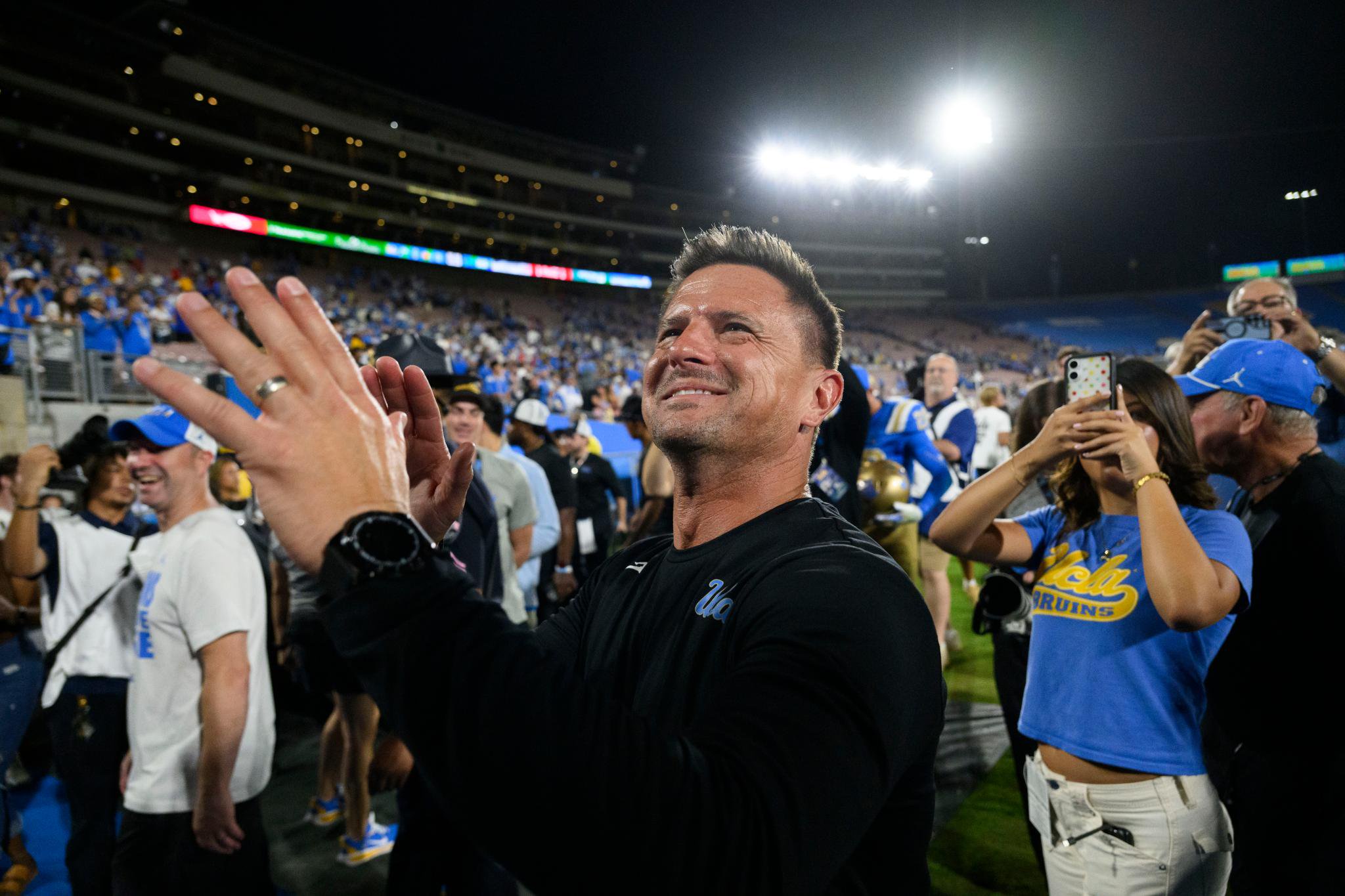 Bob Chesney clapping and smiling at a stadium at night.
