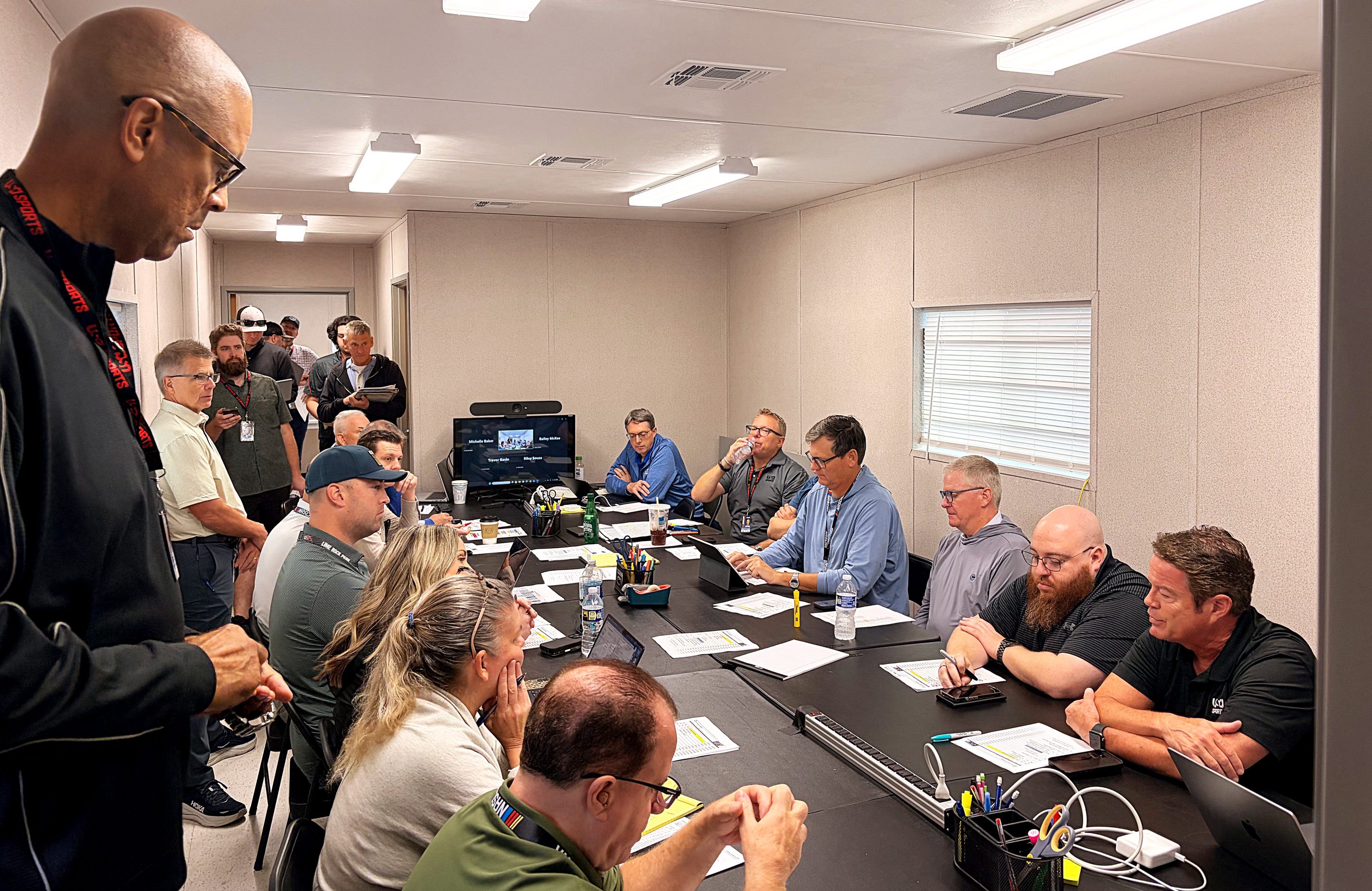 Members of USA Sports' production crew crowd inside a trailer at Charlotte Motor Speedway on the morning of the Bank of America 400 for a pre-race meeting on Sunday, Oct. 11, 2026.