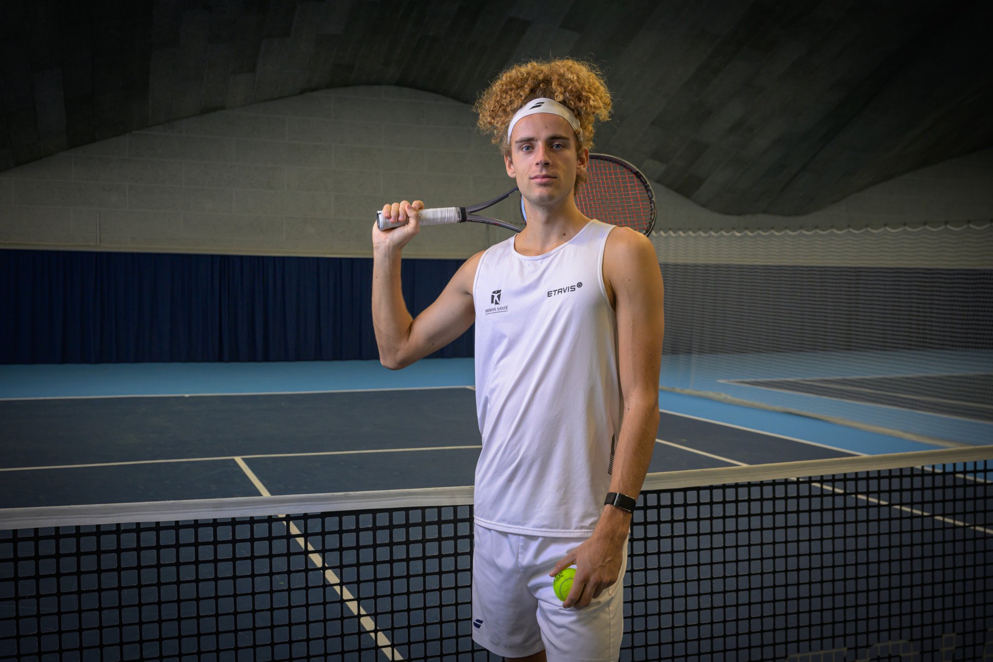 Tennistalent Mika Brunold posiert mit Schläger und Ball am Netz im Tenniscenter Paradies in Allschwil.