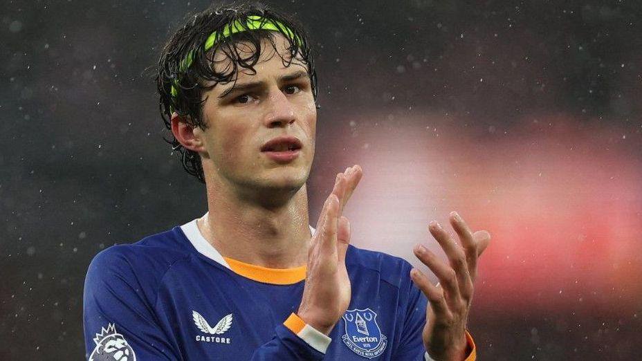 Everton's Merlin Röhl applauds fans after the match on 26 October. He is wearing a blue Everton kit and it is raining. 