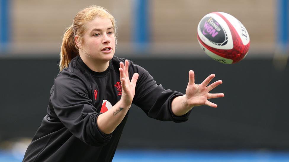 Bethan Lewis in black Wales training top holds her hands forward ready to catch an approaching rugby ball 