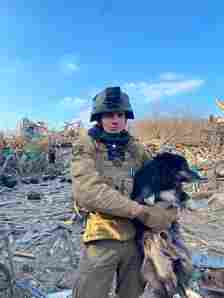 ARK member holds a dog in front of rubble