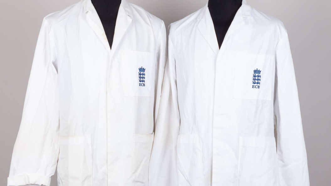 Picture of two umpire jackets, in white. They have the ECB branding stitched to the left hand side on a breast pocket. Two patch pockets are sewn below that.