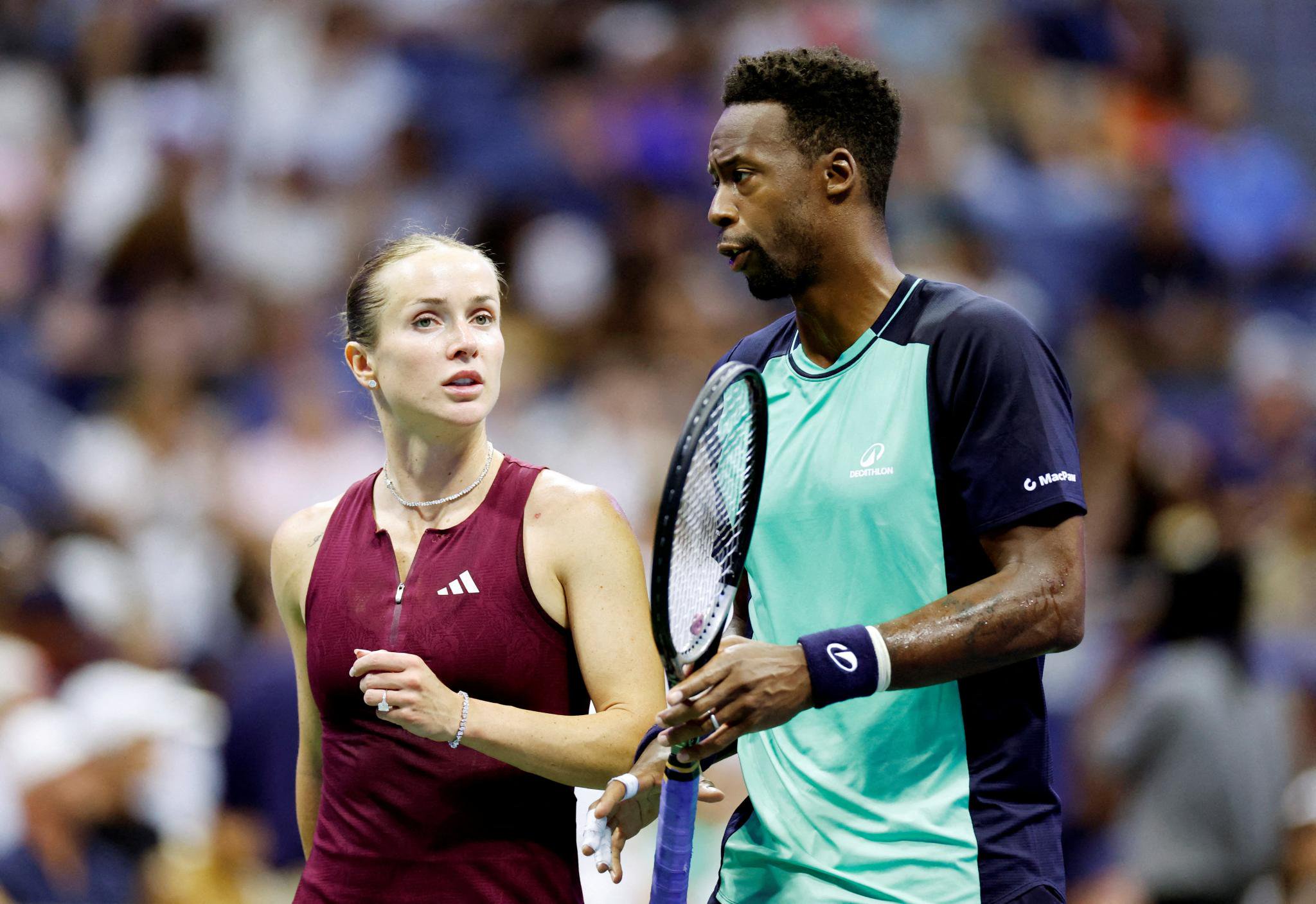 Elina Svitolina and Gael Monfils stand on a tennis court during their mixed doubles match.