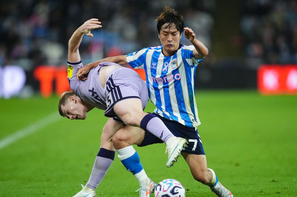 Coventry City's Tatsuhiro Sakamoto and Newcastle United's Lewis Hall battle for the ball 