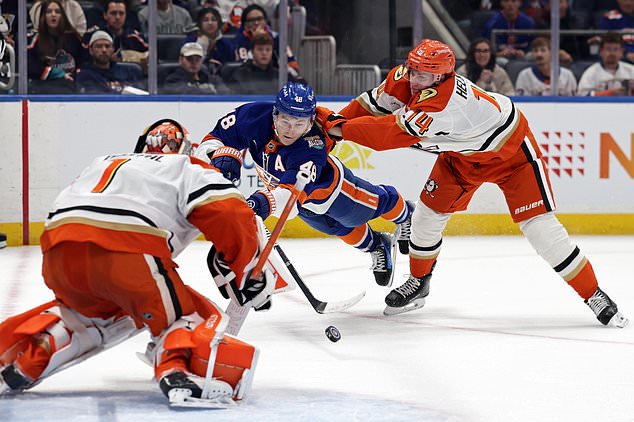 New York Islanders defenseman Matthew Schaefer (48) shoots towards Anaheim Ducks goaltender Lukas Dostal as he is pushed by Ducks defenseman Drew Helleson (14) during the second period of an NHL hockey game Tuesday, Oct. 20, 2026, in Elmont, N.Y. (AP Photo/Adam Hunger)