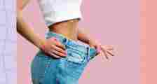 woman dropping pants and jeans size concept on pink background