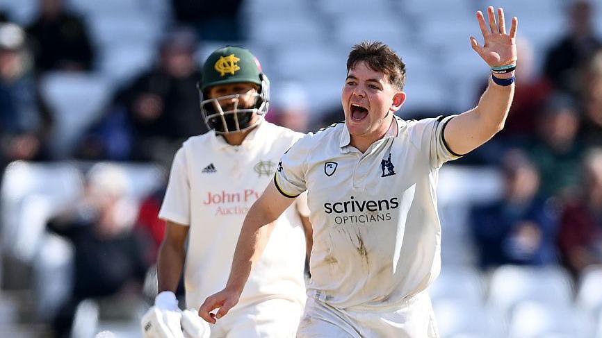 Ethan Bamber raises his left arm in celebration after taking a wicket