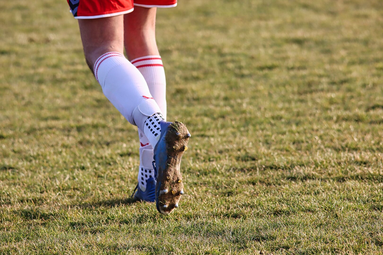 Nahaufnahme der Beine eines Spielers mit blauen Fußballschuhen