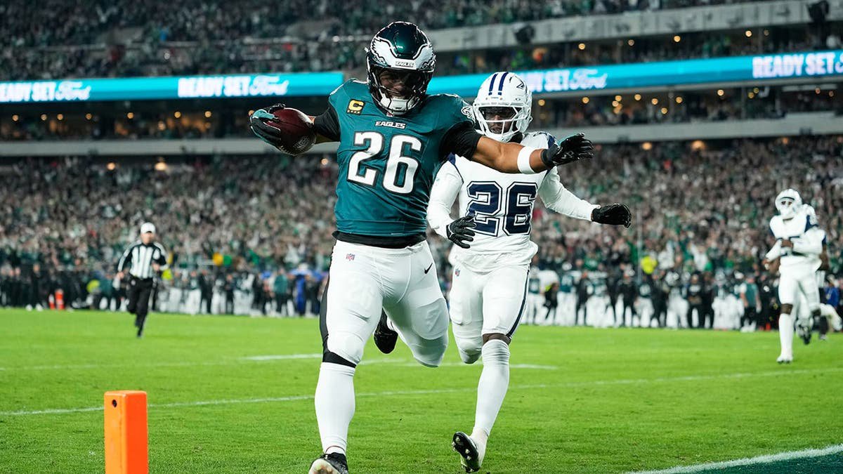 Saquon Barkley runs for a touchdown past Dallas Cowboys cornerback Daron Bland during an NFL game.