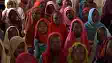 A group of Sudanese school girls sit on the floor in a classroom