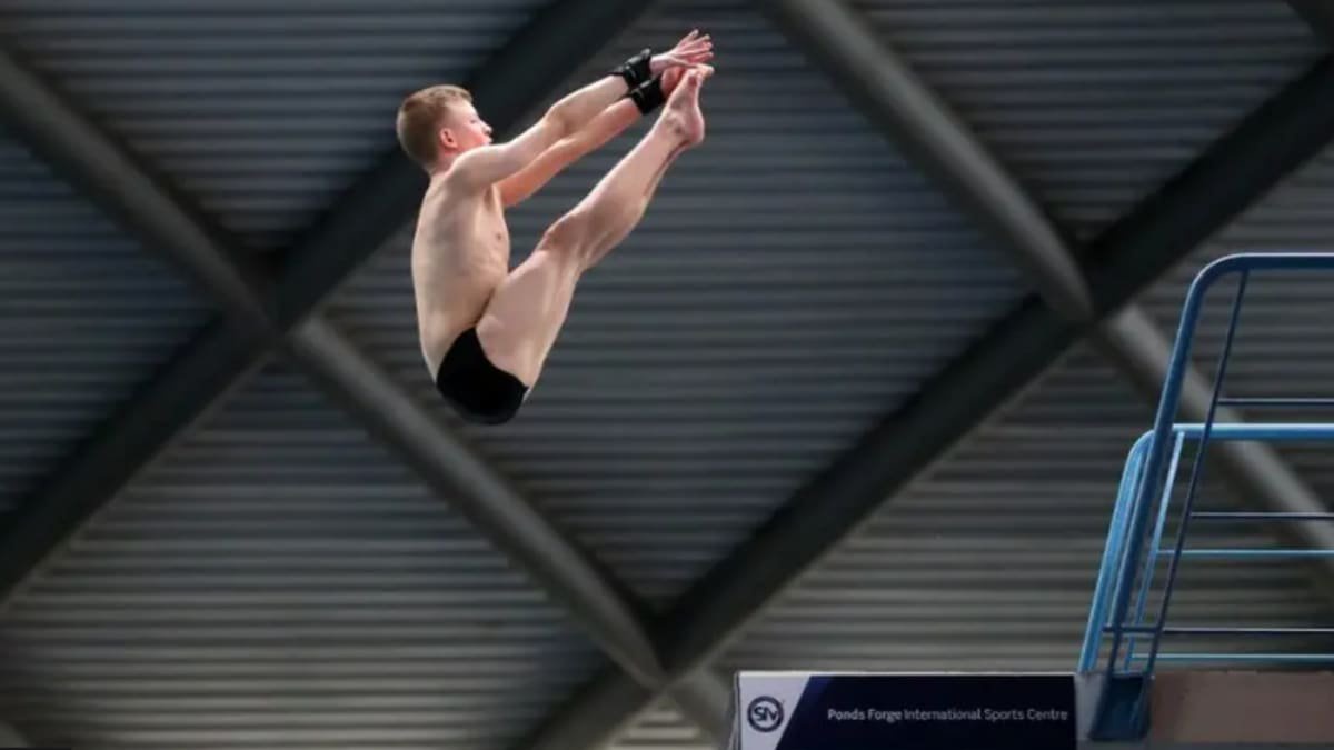 A young diver leaps in the air touching his toes off a high board