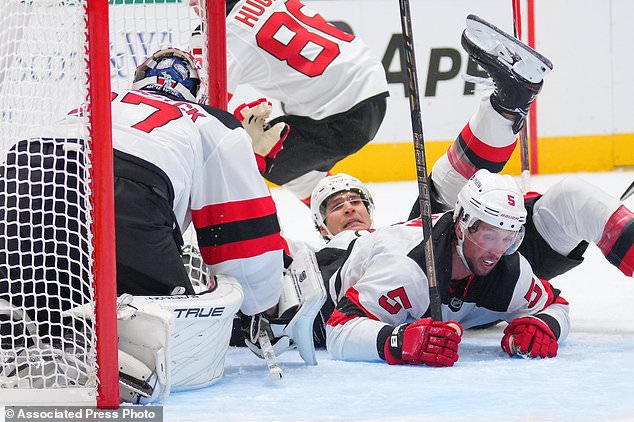 New Jersey Devils goaltender Connor Hellebuyck, left, defenseman Johnathan Kovacevic, center, and defenseman Brenden Dillon, right,, collide while defending their net against the Dallas Stars during the first period of an NHL hockey game Tuesday, Oct. 27, 2026, in Dallas. (AP Photo/Julio Cortez)