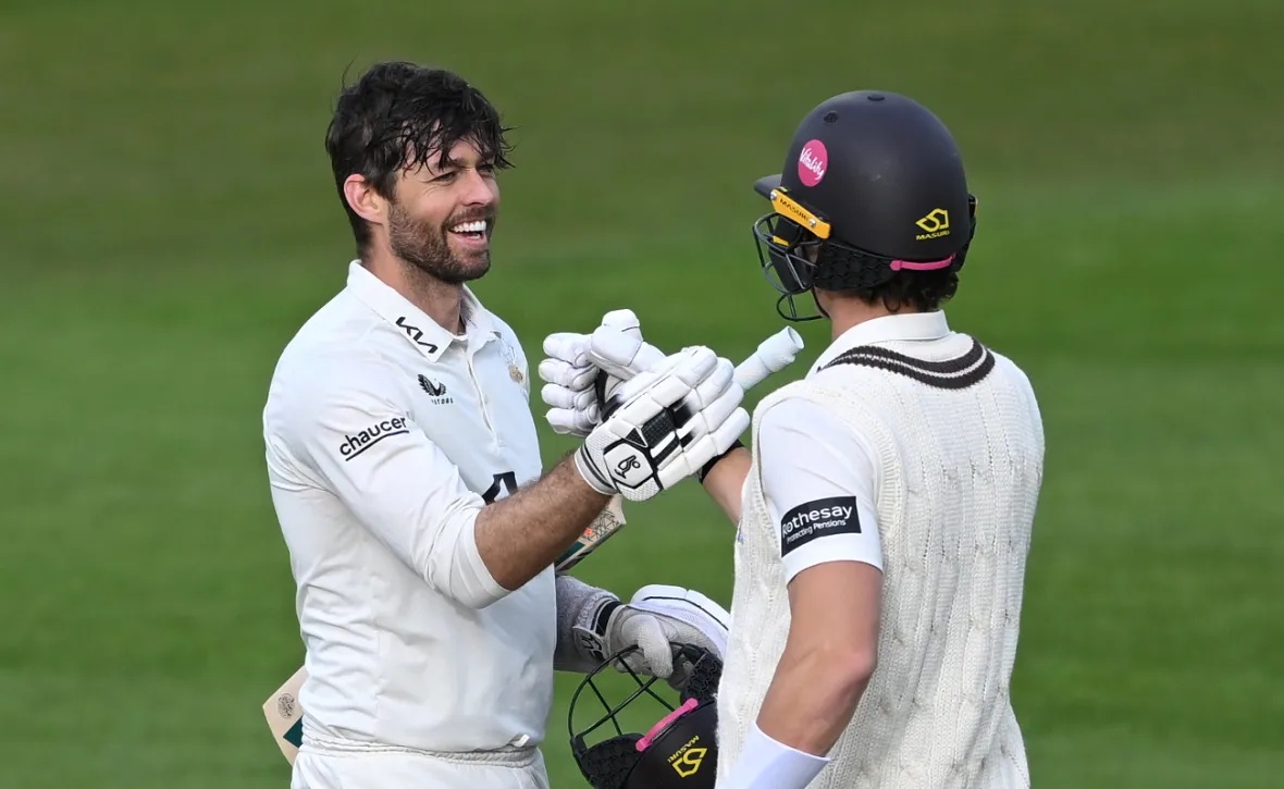 Ben Foakes of Surrey celebrates his century with teammate Sean Abbott during a cricket match.