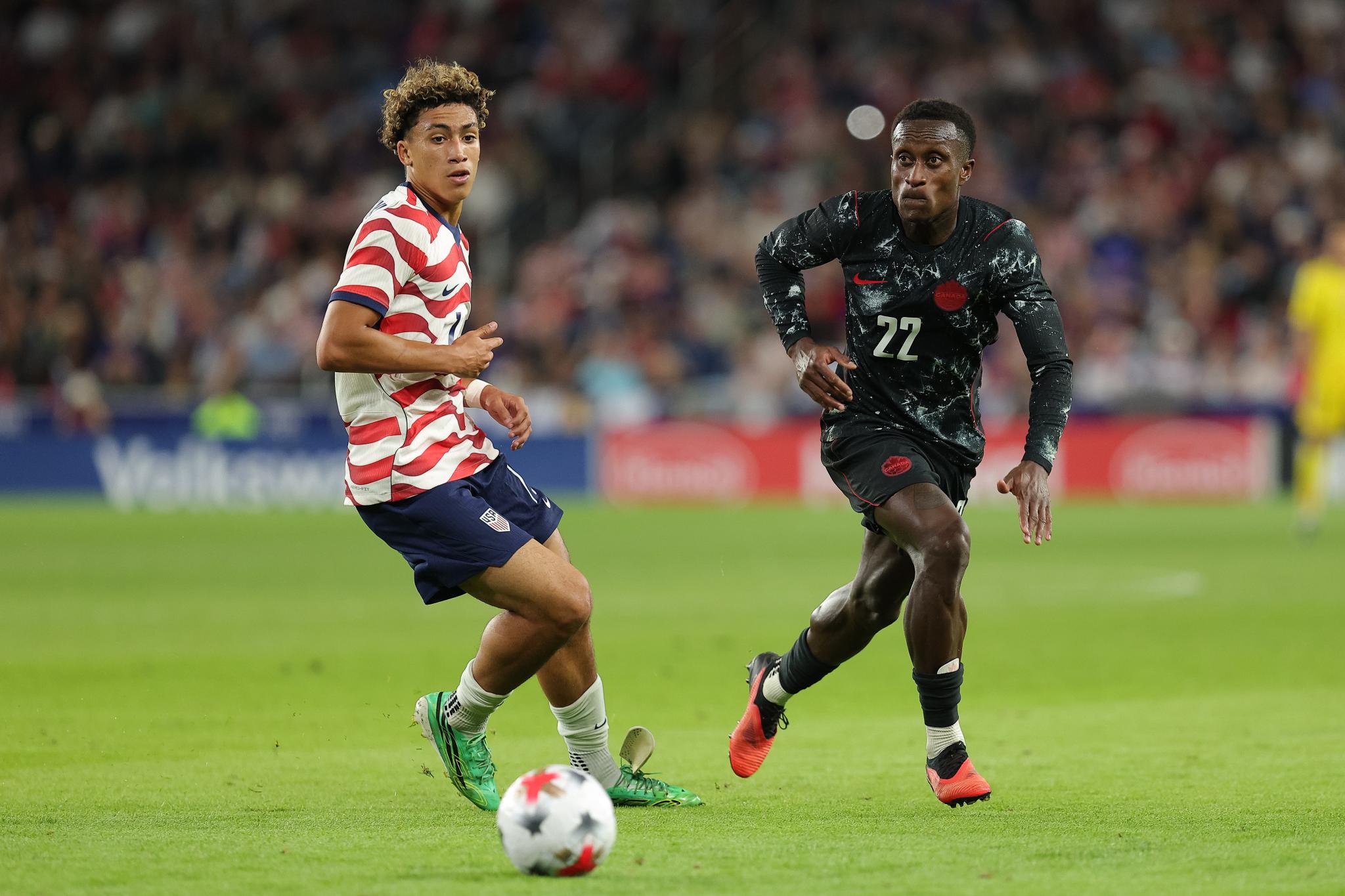 USA and Canada soccer players competing for the ball.