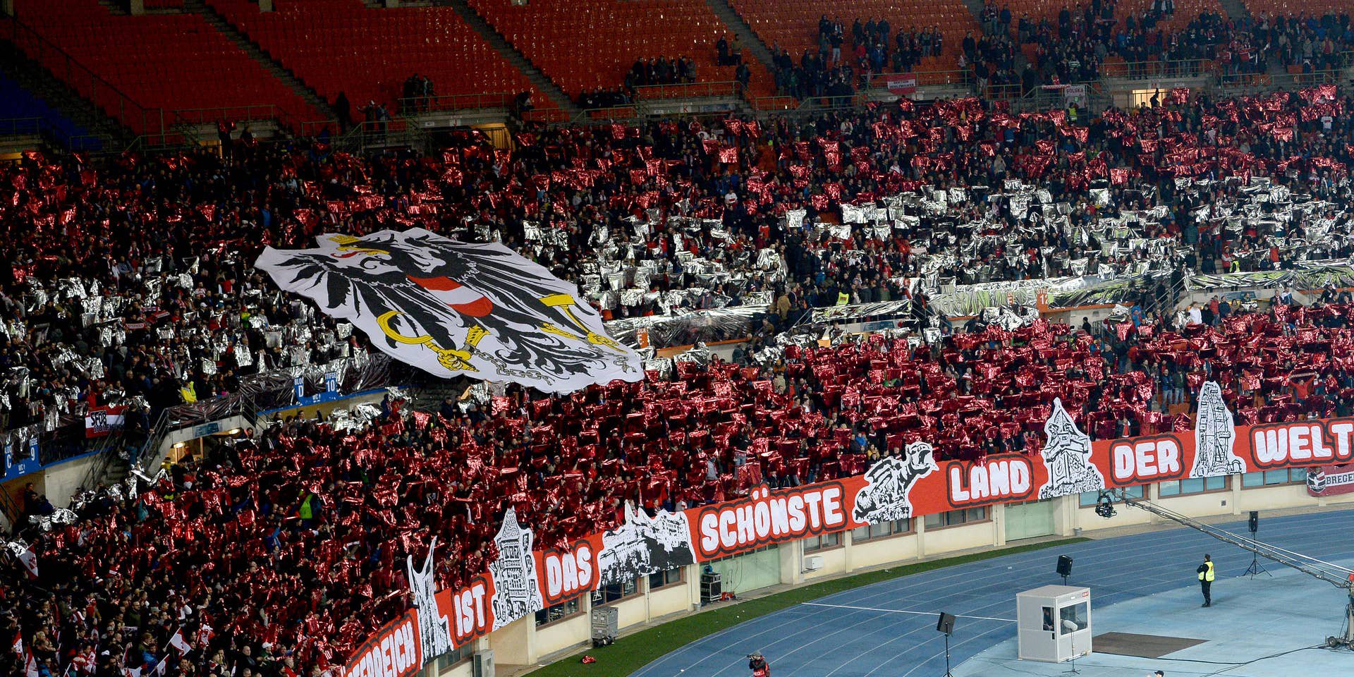 Österreichische Fans mit rotem Glanzpapier und großer Adler-Fahne im Ernst Happel-Stadion, Wien.
