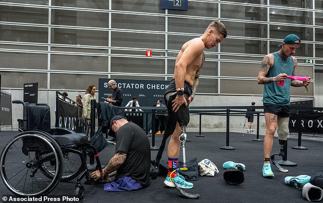 From left, Ukrainian veterans Dmytro Bykhovchenko, Ivan Artiukh and Oleksii Doroshenko warm up at the HYROX competition in Valencia, Spain, Sunday, Oct. 18, 2026. (AP Photo/Alberto Sáiz)