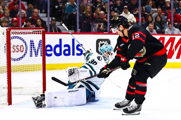 San Jose Sharks goaltender Yaroslav Askarov (30) makes a save against Ottawa Senators' Shane Pinto (12) during the second period of an NHL hockey game in Ottawa, Ontario, Thursday, Oct. 22, 2026. (Keito Newman/The Canadian Press via AP)