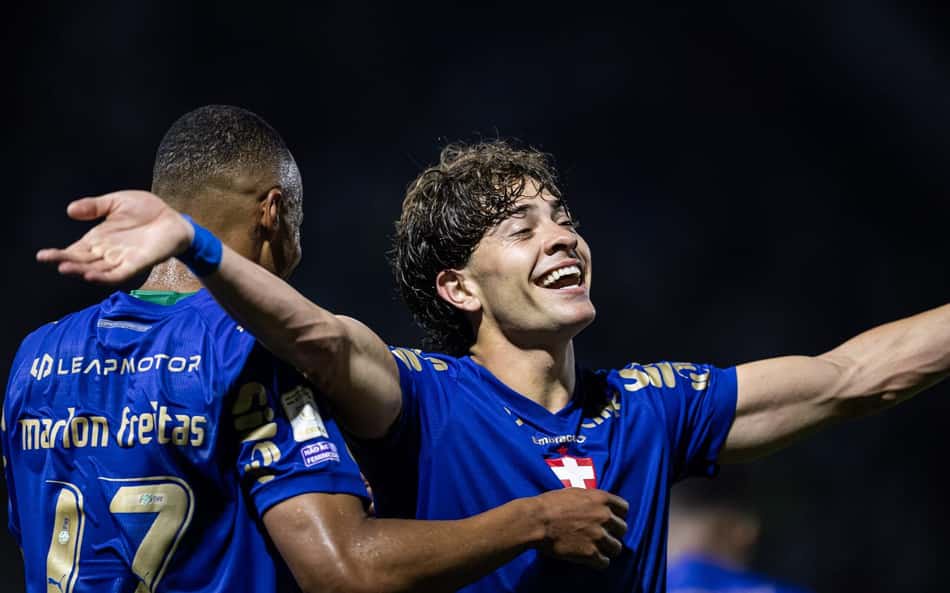 Dois jogadores do Palmeiras celebram com braços abertos em jogo noturno