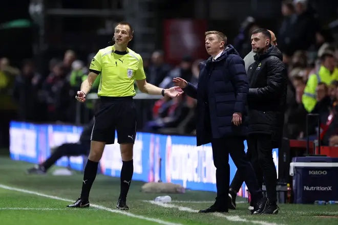 Referee Michael Salisbury speaks to a member of Fleetwood Town staff as the game is paused due to a drone being spotted above the pitch