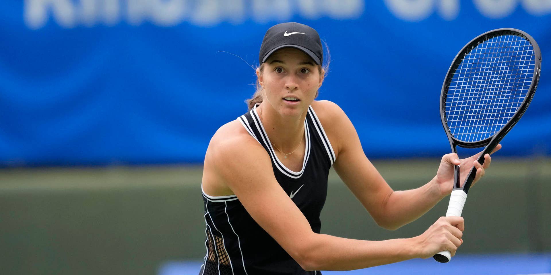 Eine Tennisspielerin schlägt einen Ball während eines Doppeltspiels in einer Halle.