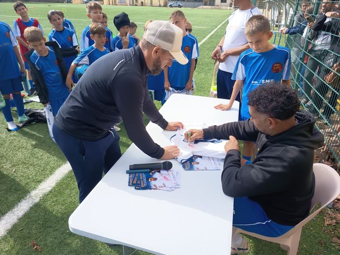 Sous le regard admiratif des jeunes footballeurs, l’ancienne star de l’OM se prête au jeu des dédicaces, accompagne de Sylvain Reynouard.