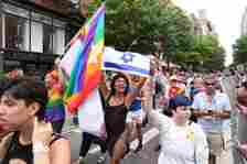 Pride parade crowd, person in bathing suit and fishnets holding an israel flag prominently featured.