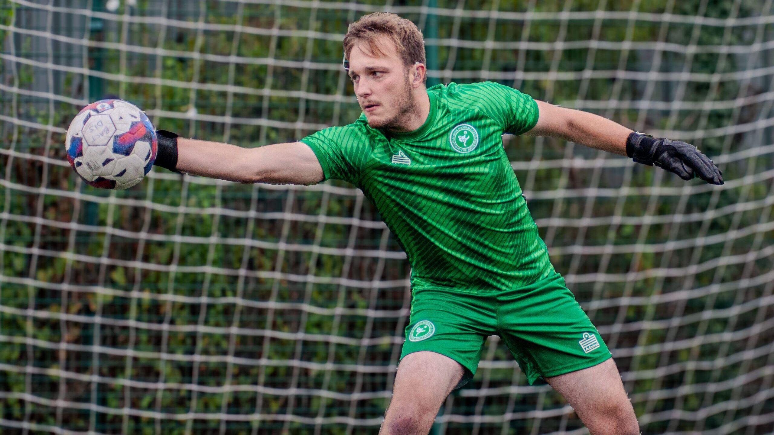 Freddie Lamb dressed in a green goalkeeper kit, catching a ball in his right hand.