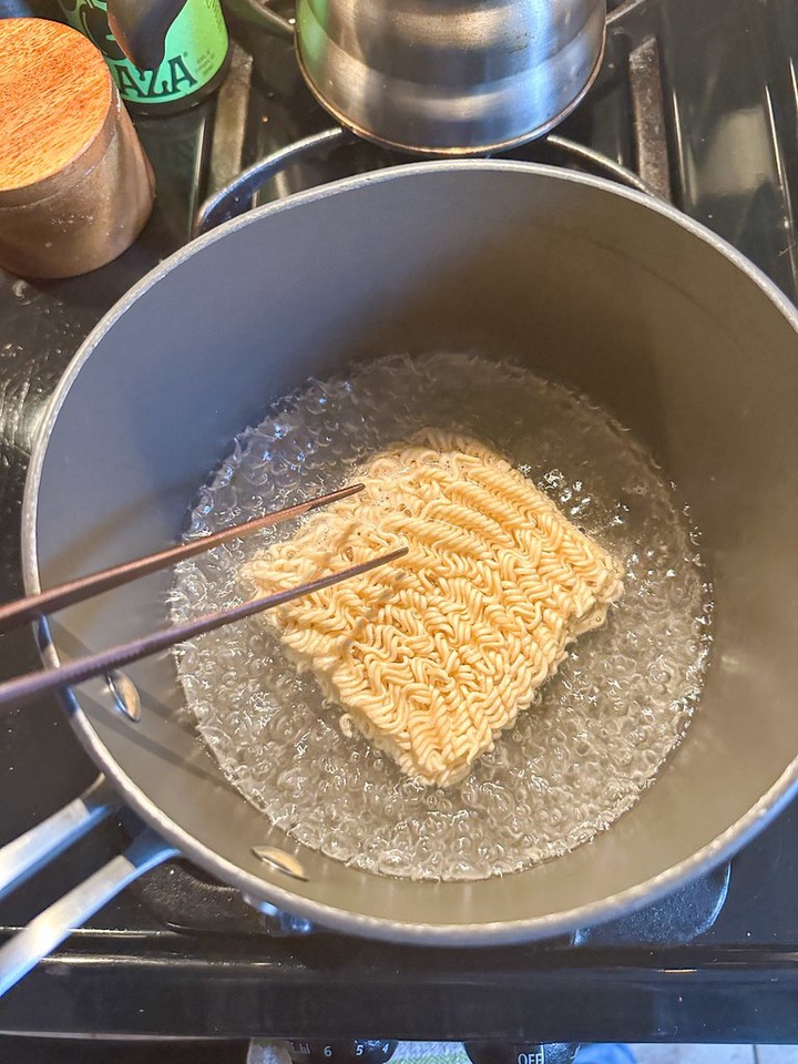 author stirring around instant ramen in boiling water