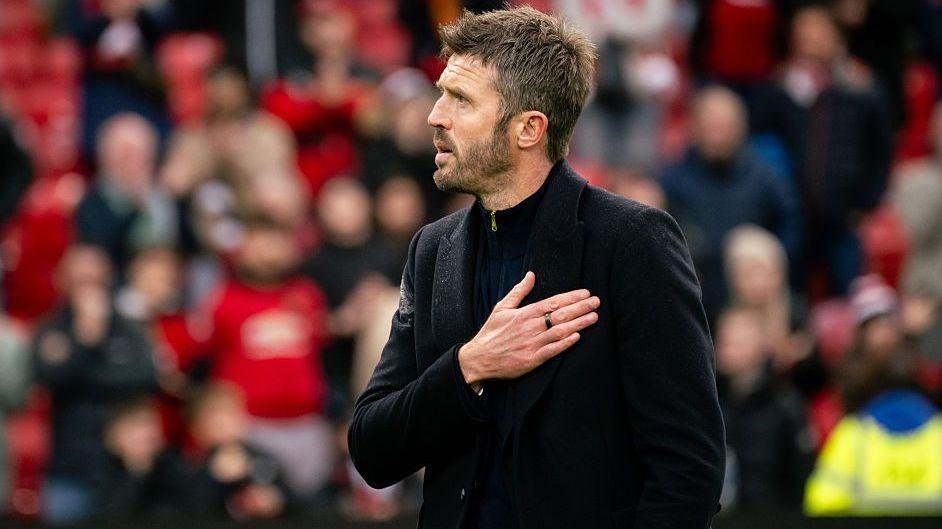 Michael Carrick looks at the supporters holding his hand on the Man Utd crest