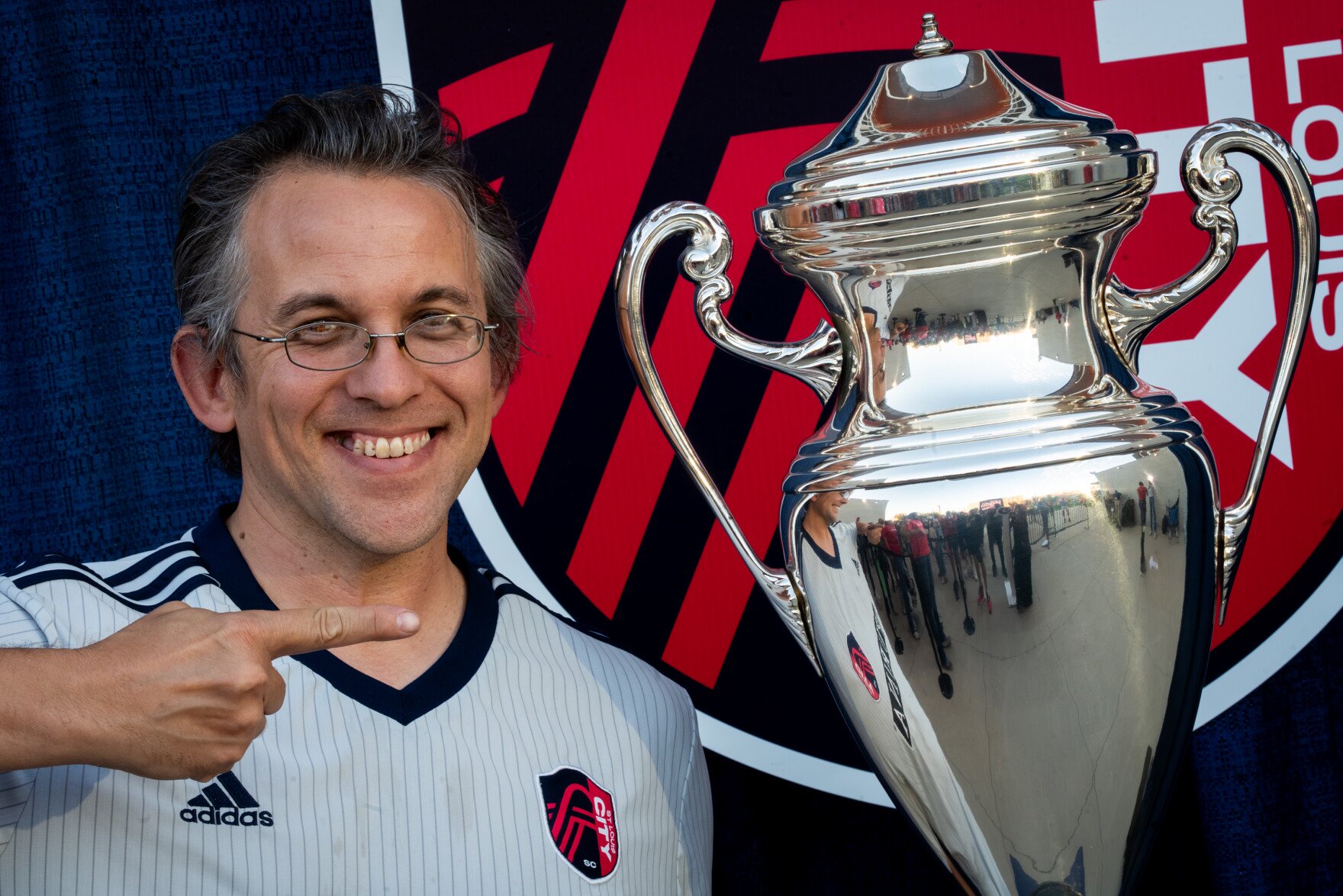 Jesse Nenninger, of Tower Grove East, points to the Lamar Hunt U.S. Open Cup trophy during a photo opportunity outside Energizer Park on Wednesday, Oct. 28, 2026, in the city’s Downtown West neighborhood.