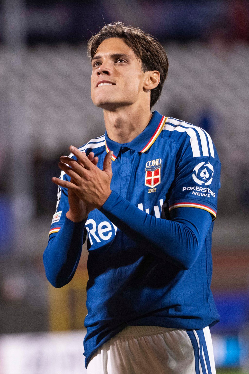 A Como 1907 player applauds during a match against Manchester United.