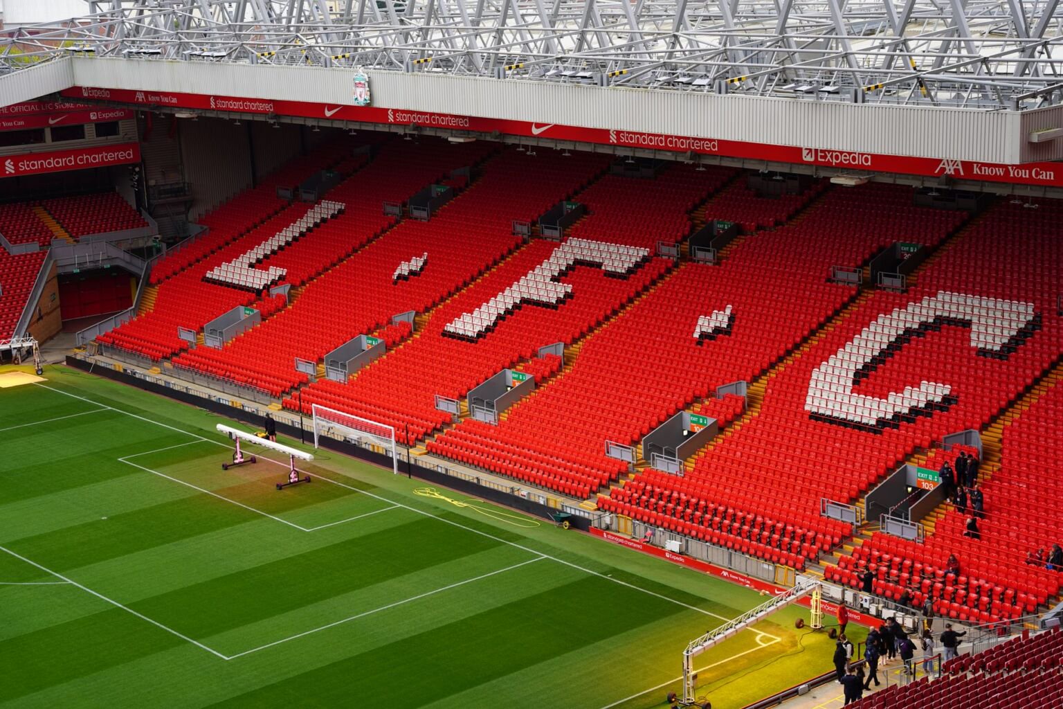 Empty red stand at Anfield with LFC spelled out in white seats beside the pitch