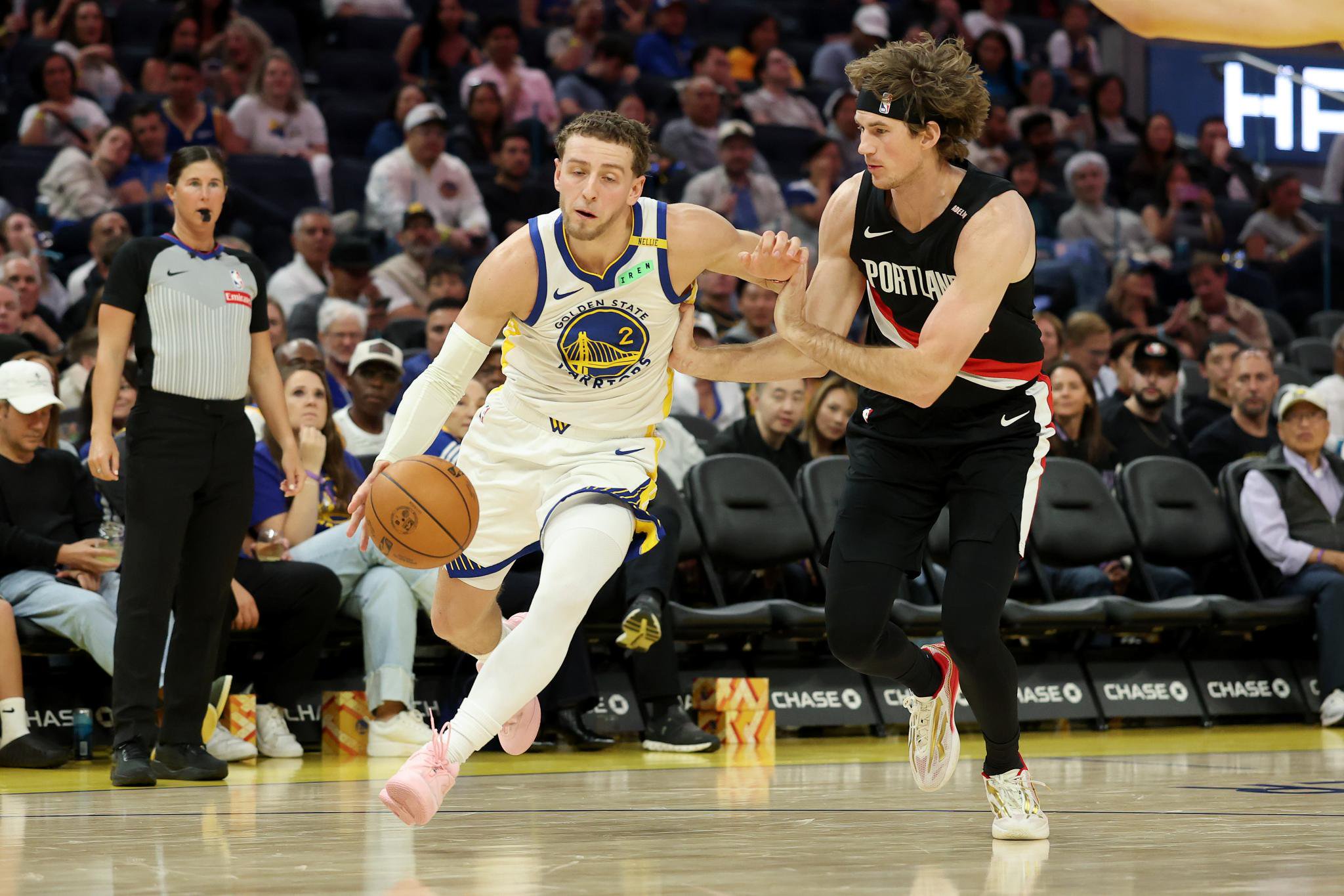 Golden State Warriors guard Brandin Podziemski dribbles the ball past Portland Trail Blazers center Branden Carlson during a game.