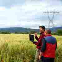 Two farmers in a wheat field with a laptop.