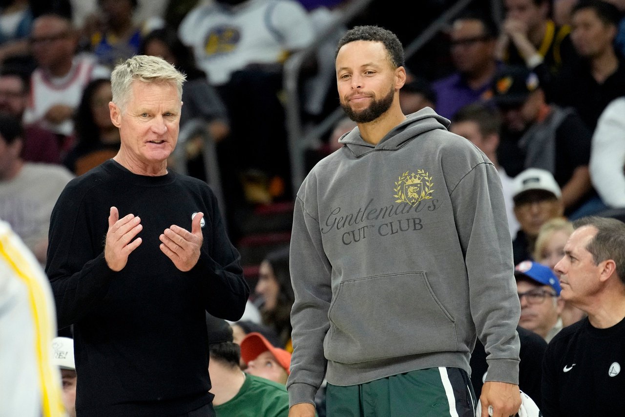Golden State Warriors head coach Steve Kerr, left, talks with Warriors' Stephen Curry during an NBA basketball game against the Phoenix Suns, Saturday, Oct. 24, 2026, in Phoenix. (AP Photo/Ross D. Franklin)