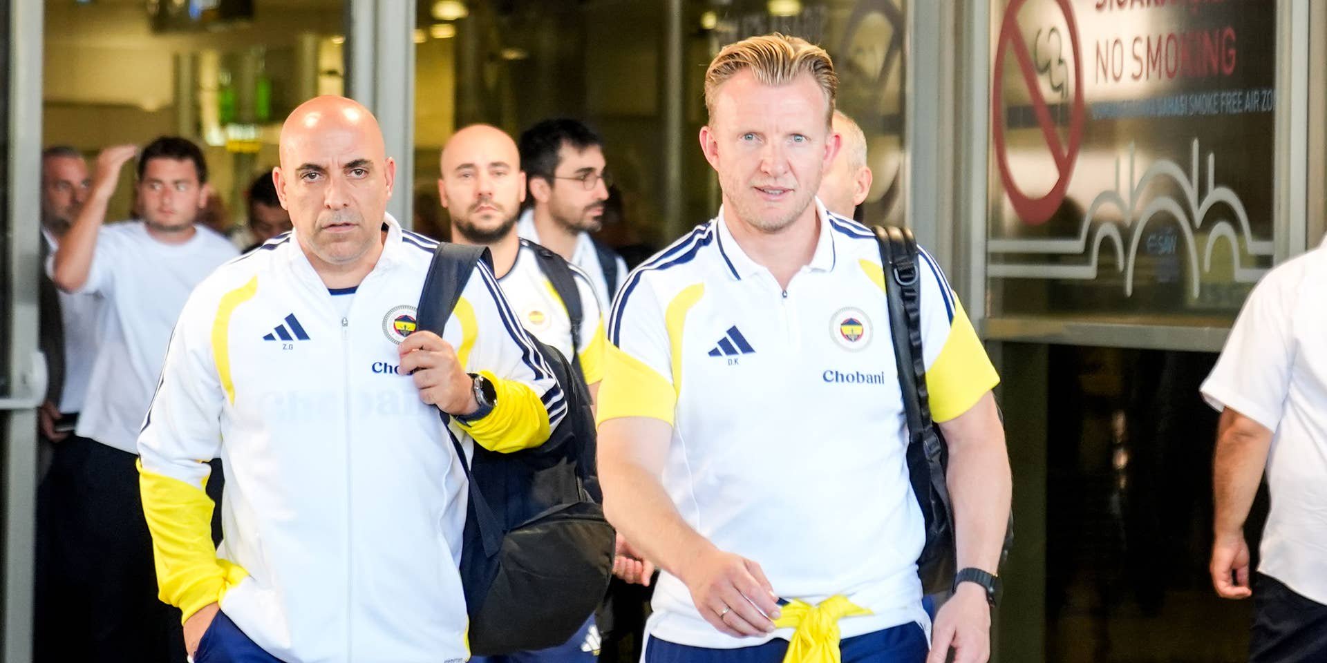 Dirk Kuyt geht gemeinsam mit einem Betreuer in Trainingskleidung von Fenerbahçe Istanbul durch einen Flughafenausgang.