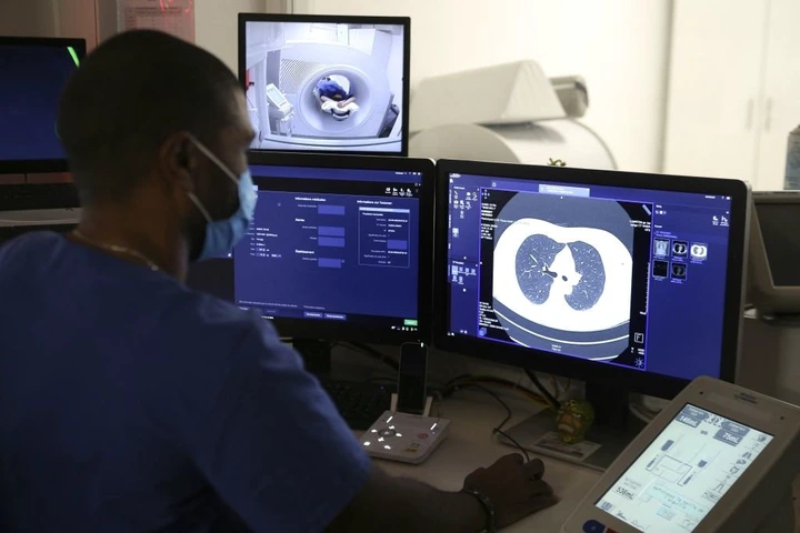 Healthcare professional analyzing a CT scan of lungs on computer screens