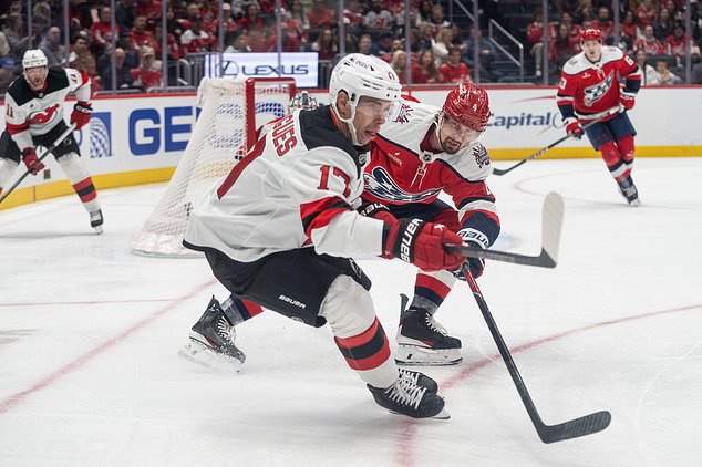 Washington Capitals defenseman Justin Holl (4) stick checks New Jersey Devils center Evan Rodrigues (17) during the second period of an NHL hockey game against New Jersey Devils, Saturday, Oct. 17, 2026, in Washington. (AP Photo/Nathan Howard)